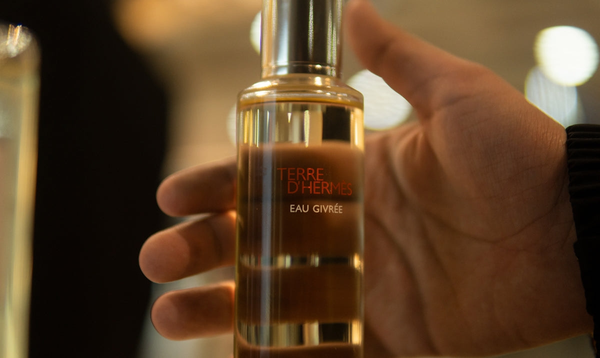 a person holding a bottle of perfume in their hand