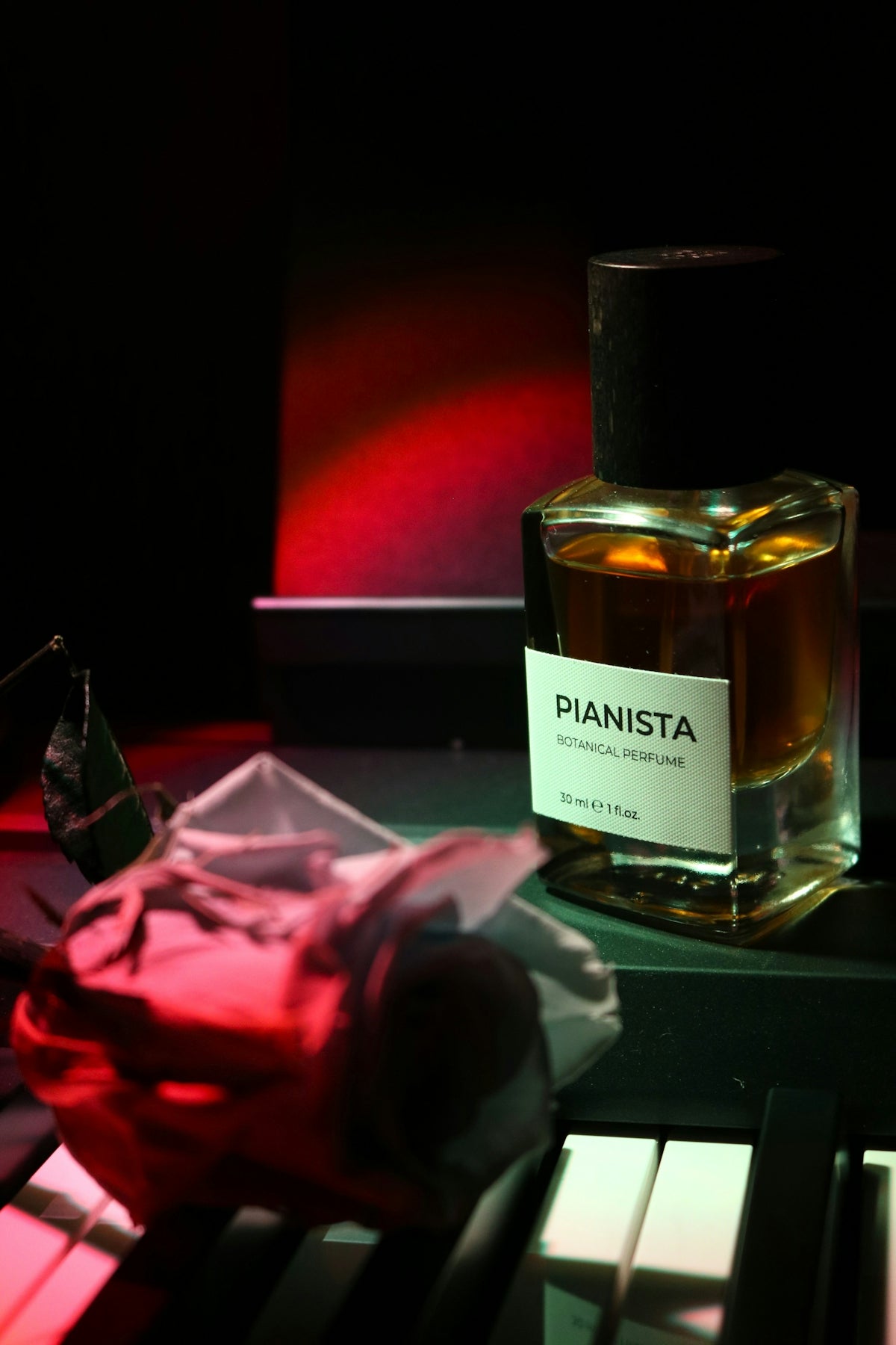 Perfume bottle with rose on piano keys